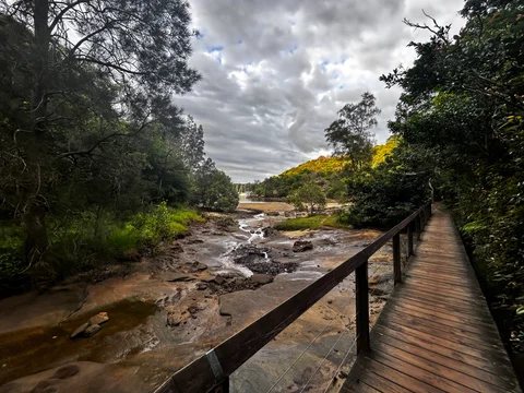A wooden bridge over a river with a view of the water and the surrounding forest.