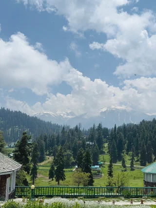  The image depicts a serene and picturesque scene of a lush green field with a mountain range in the background. The field is dotted with trees, creating a sense of tranquility and natural beauty. The sky above is filled with clouds, adding a sense of depth and dimension to the landscape. The overall mood of the image is one of peace and harmony, as the viewer takes in the breathtaking view of the mountains and the verdant field below.