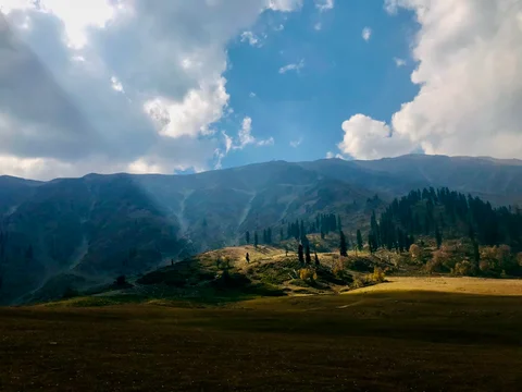 A beautiful mountain landscape with a sun shining on it.