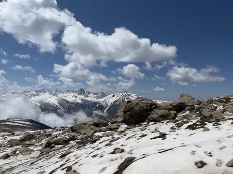 A snowy mountain with a cloudy sky above it.