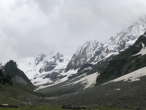 A mountain range with snow on the peaks and a valley below.