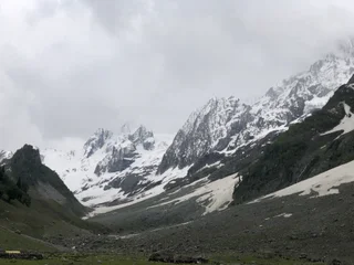  The image depicts a breathtaking mountain landscape with a vast expanse of snow-covered mountains. The mountains are adorned with a dusting of snow, creating a serene and tranquil atmosphere. The scene is further enhanced by the presence of a few trees scattered throughout the landscape, adding a touch of natural beauty to the otherwise barren environment. The overall mood of the image is one of awe and wonder, as the viewer is struck by the sheer scale and beauty of the mountain range.