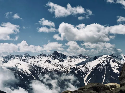A mountain range with snow and clouds in the background.